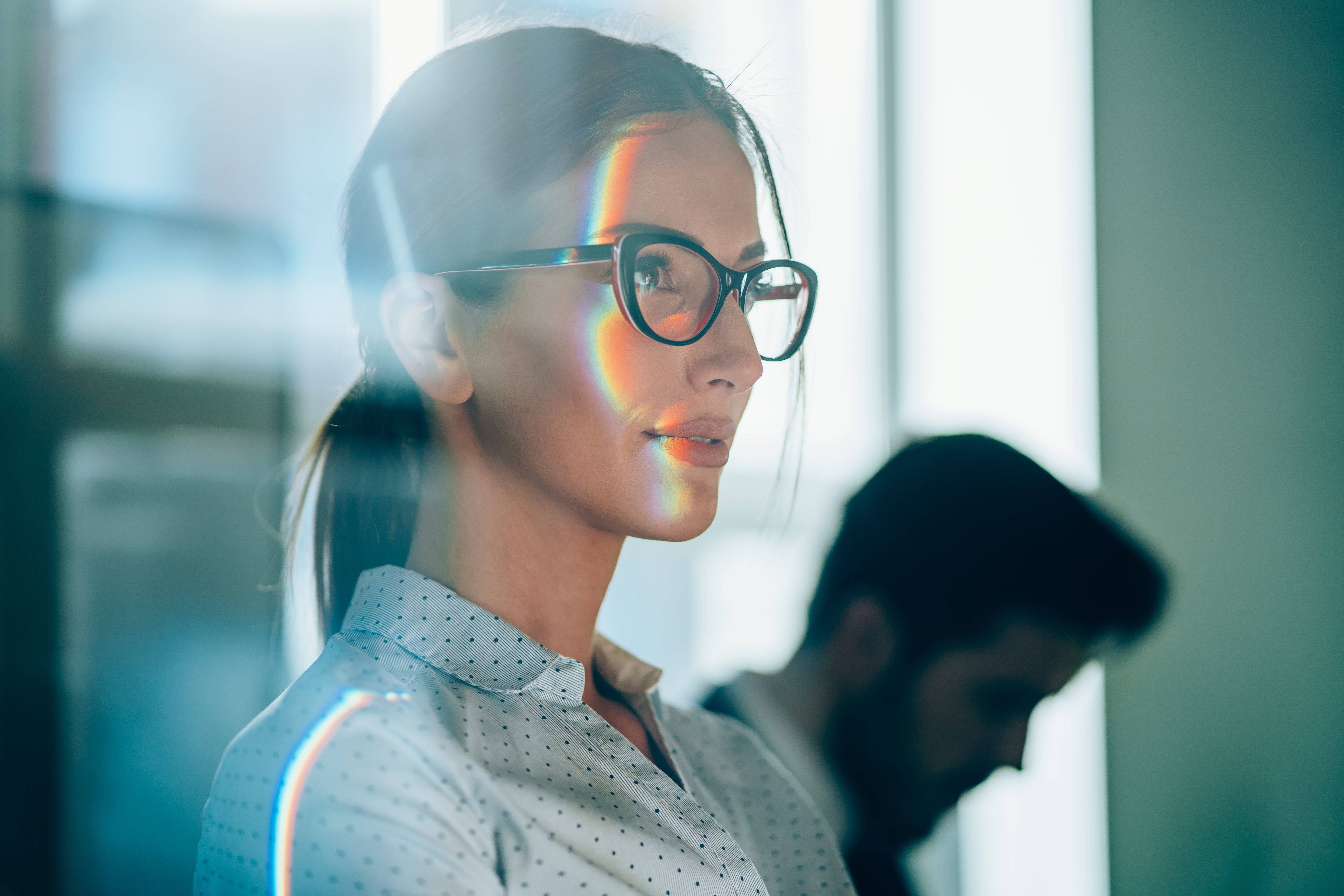 Woman wearing glasses looking at a computer screen with a blurred background