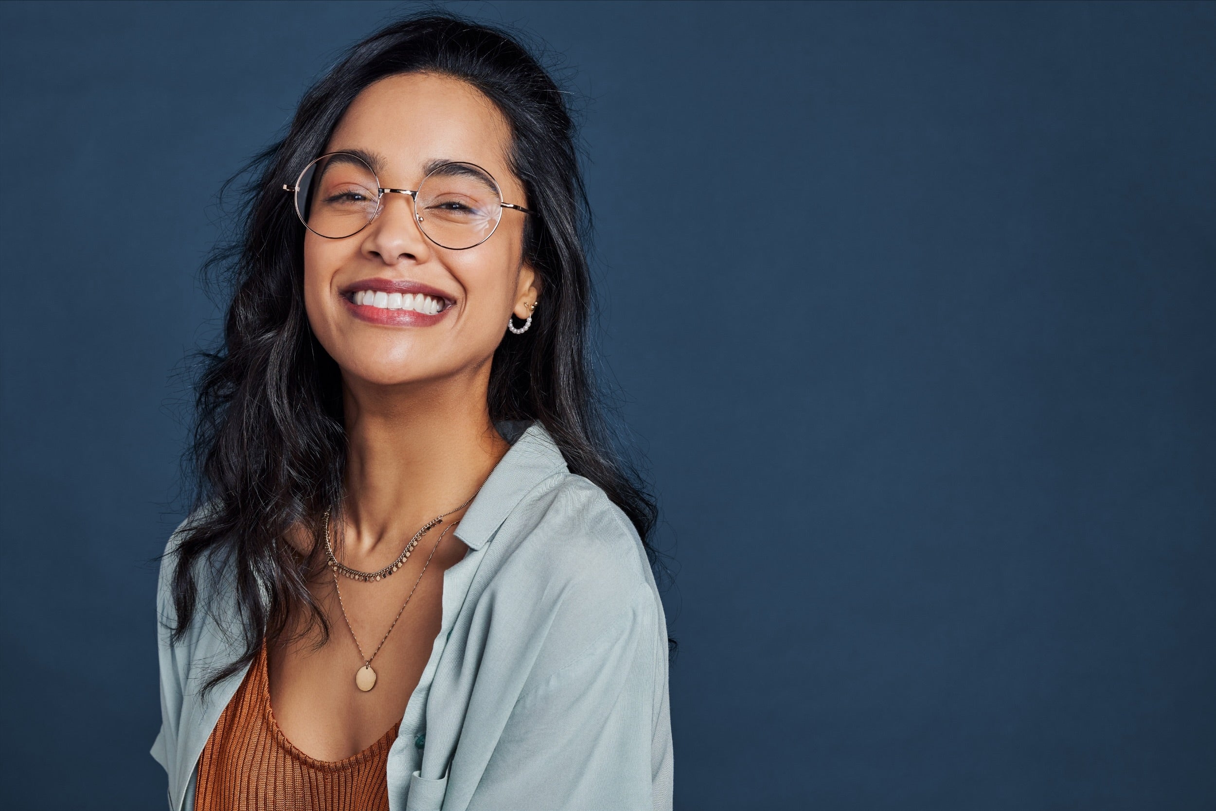 Woman wearing glasses and a light blue cardigan against a dark blue background