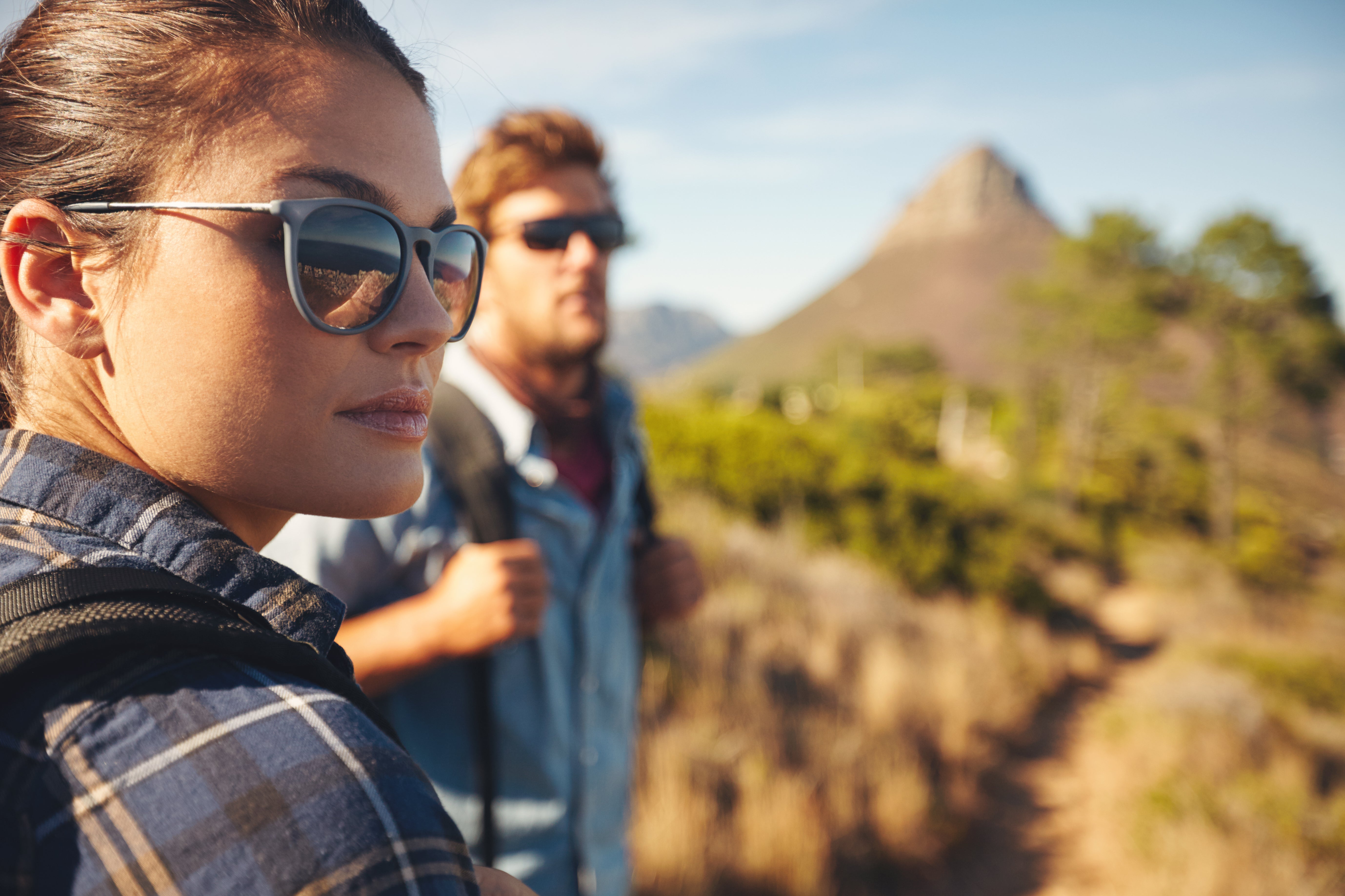 Two people hiking with sunglasses on, surrounded by nature.
