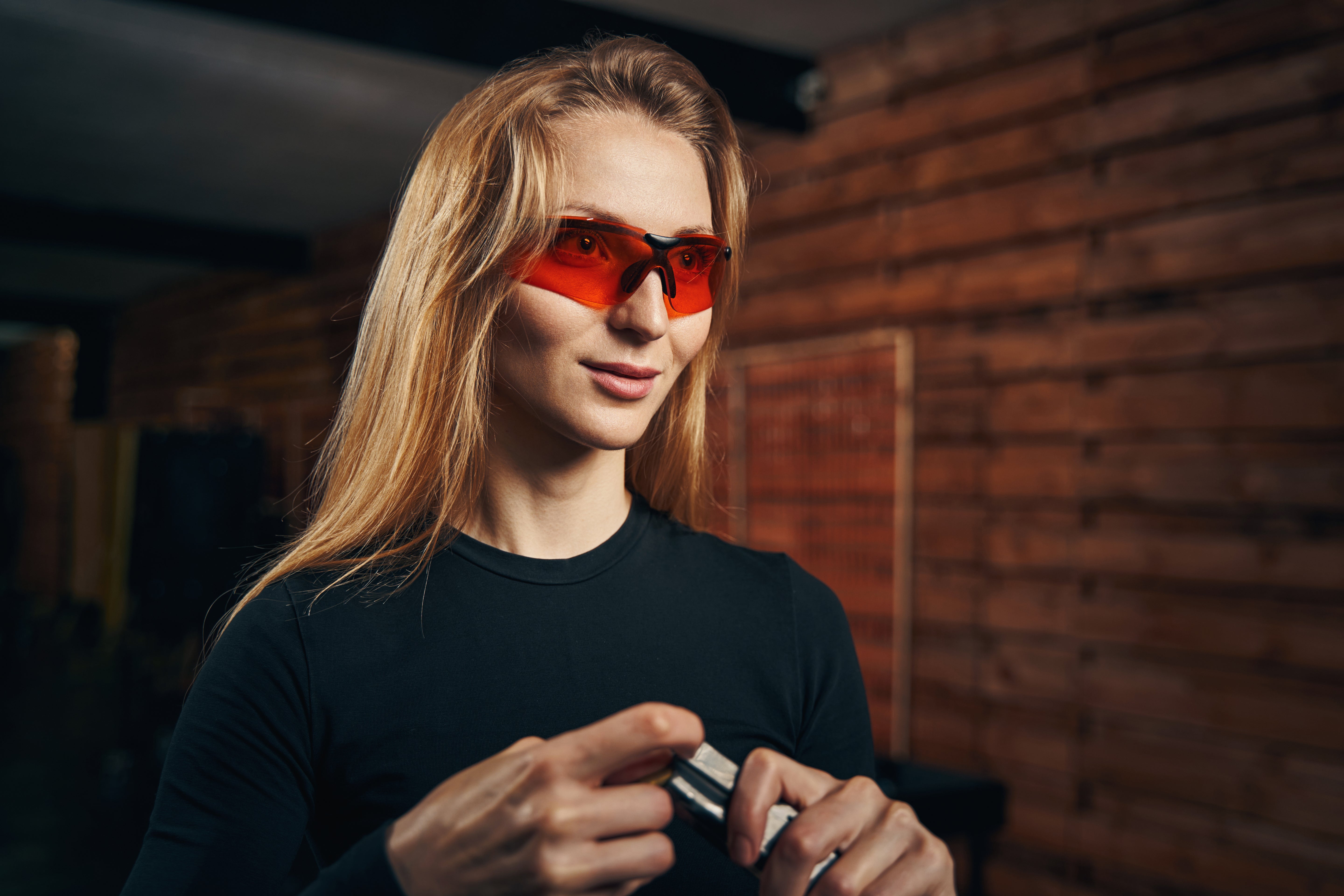 Person wearing red sunglasses in a dimly lit room with brick walls